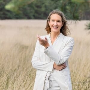 Vrouw reikt haar hand uit in de natuur, symbool voor loslaten en vertrouwen in je eigen pad.