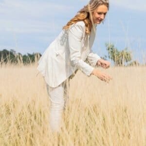 Vrouw staat krachtig en energiek in rietveld, symbool voor zelfvertrouwen en persoonlijke groei. Heeft haar Human Design Geïntegreerd