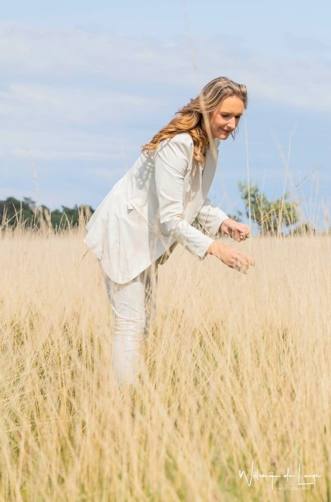 Vrouw staat krachtig en energiek in rietveld, symbool voor zelfvertrouwen en persoonlijke groei. Heeft haar Human Design Geïntegreerd